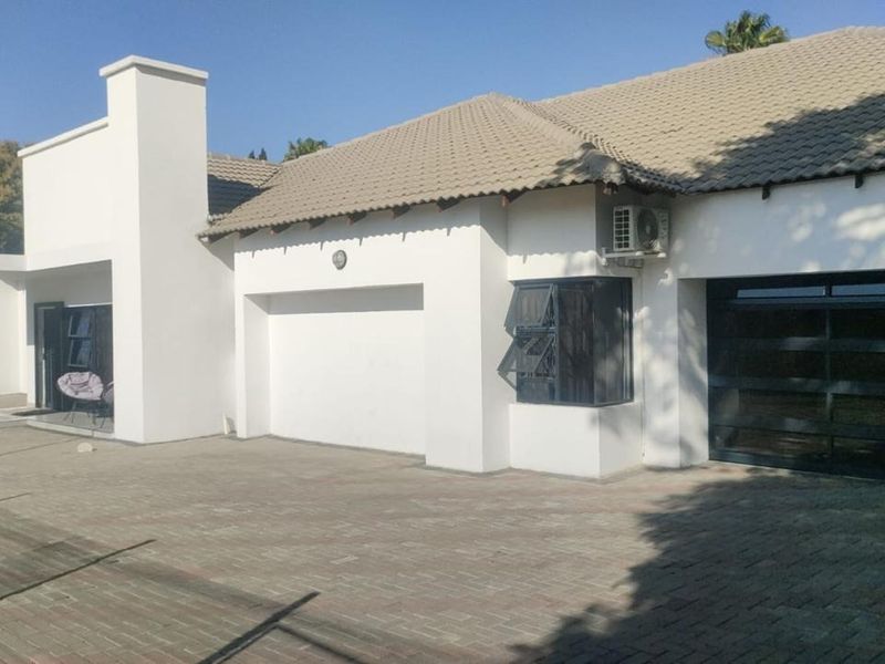Front elevation of a modern house featuring a paved driveway, tiled roof, and integrated garage access.