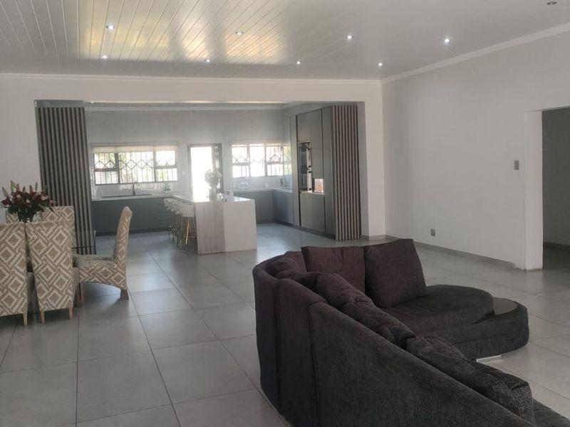 Spacious open-plan living area featuring large format floor tiles, recessed lighting, and a modern kitchen with a central island and integrated cabinetry.