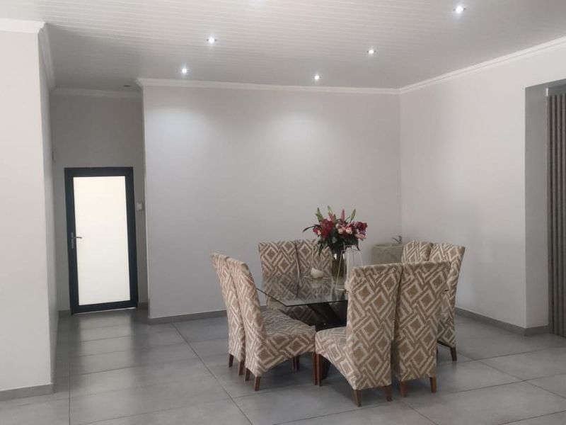 Spacious dining area featuring large format floor tiles, recessed downlighting, and a modern slatted timber feature wall.