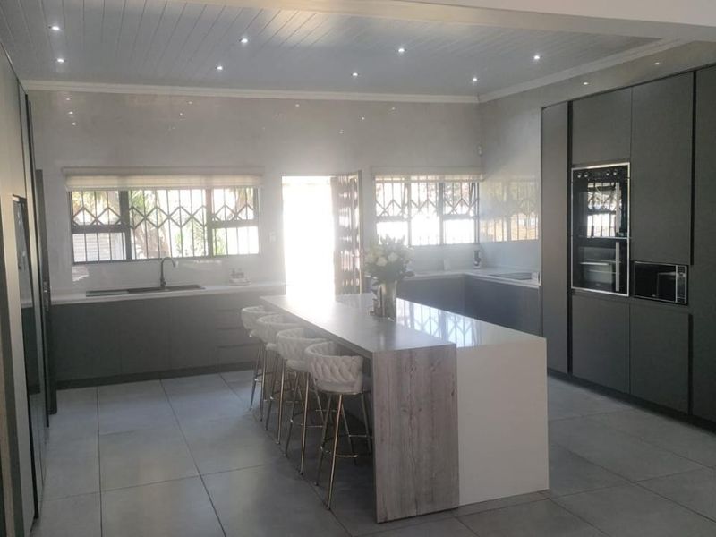 Modern, high-end kitchen featuring a large central island, sleek cabinetry, built-in appliances, and contemporary tiled flooring with recessed lighting.