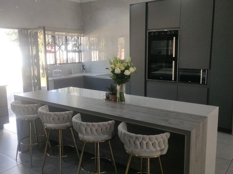 Modern kitchen featuring a large island with stone countertop, integrated appliances, and sleek cabinetry, offering a functional and contemporary cooking space.