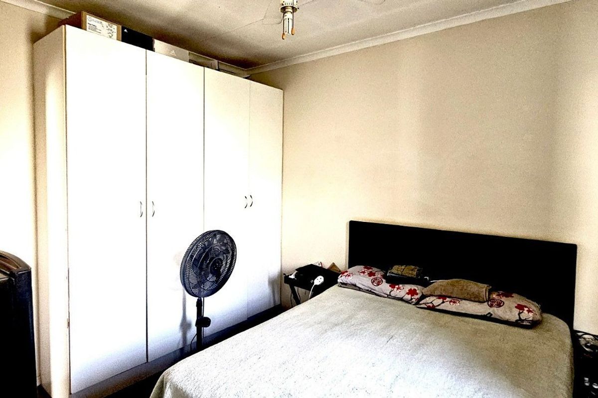 A functional bedroom featuring built-in floor-to-ceiling wardrobes and neutral wall finishes.