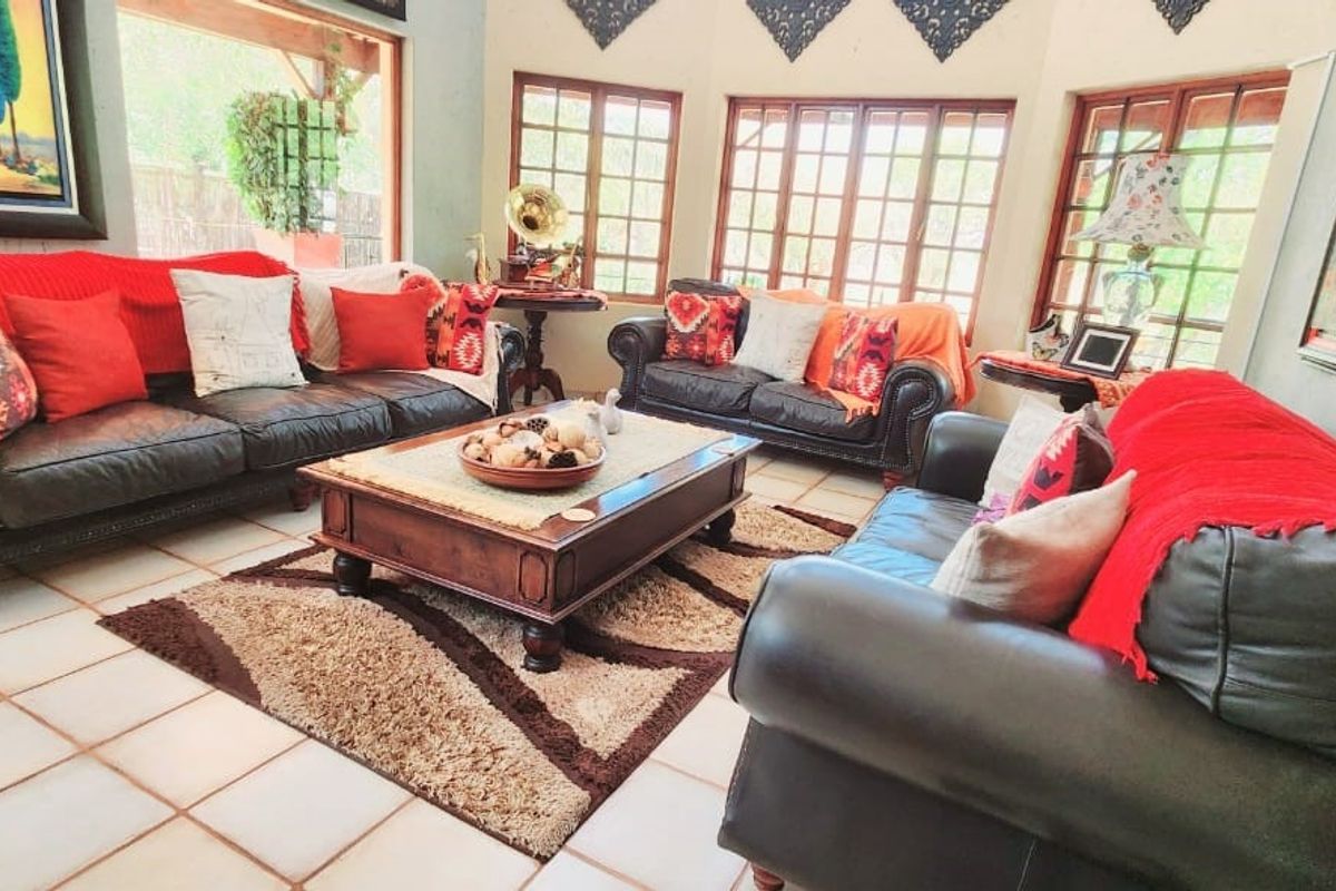 A spacious living room featuring large windows with wooden frames, tiled flooring, and a bright, airy atmosphere.