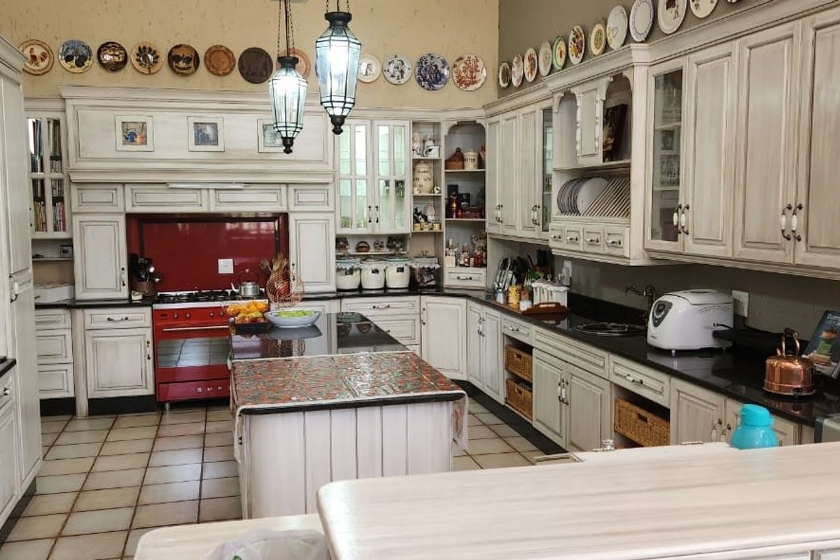 Spacious farmhouse-style kitchen featuring custom cabinetry, a central island, granite countertops, and a prominent red range cooker.