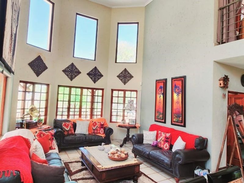 Spacious double-volume living room featuring high ceilings, large windows, tiled flooring, and a mezzanine level overlooking the main seating area.