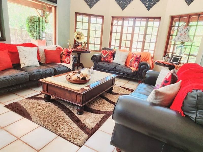 A spacious living room featuring large windows with wooden frames, tiled flooring, and a bright, airy atmosphere.