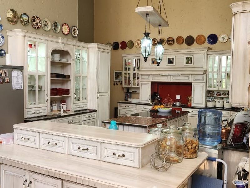 Spacious farmhouse-style kitchen featuring custom cabinetry, a central island, and integrated storage solutions with a rustic aesthetic.
