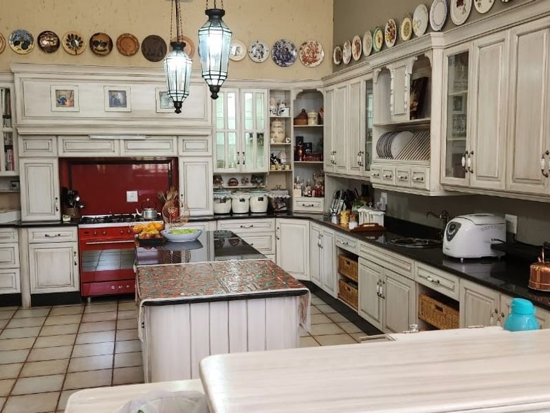 Spacious farmhouse-style kitchen featuring custom cabinetry, a central island, granite countertops, and a prominent red range cooker.