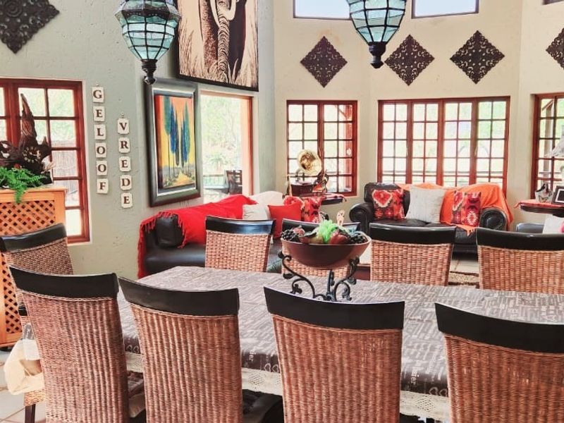 Spacious open-plan living and dining area featuring high ceilings, large windows with timber frames, and tiled flooring.