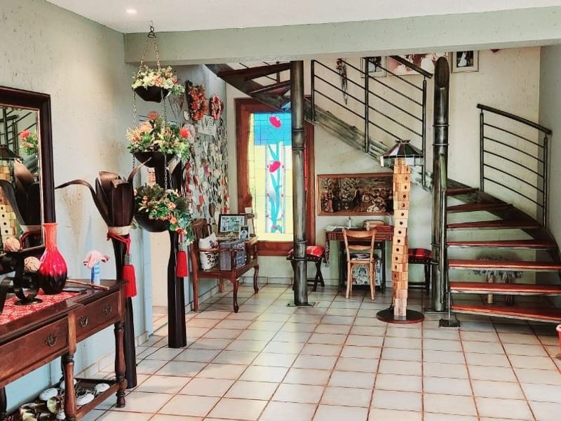 An inviting entrance hall featuring a striking spiral staircase with metal railings and tiled flooring, creating a unique architectural focal point.