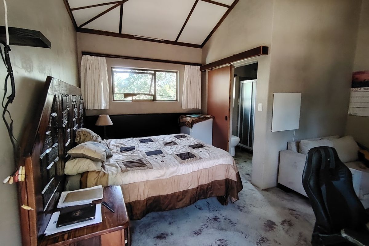 A bedroom featuring a vaulted ceiling, an attached en-suite bathroom, and a window providing natural light.