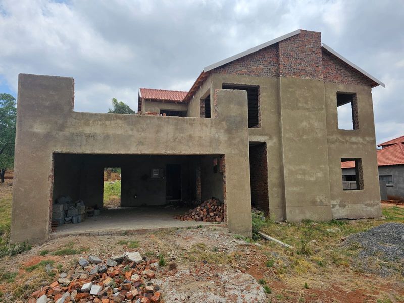 A double-story residential property currently under construction, featuring raw plastered walls, exposed brickwork, and open window and door apertures.