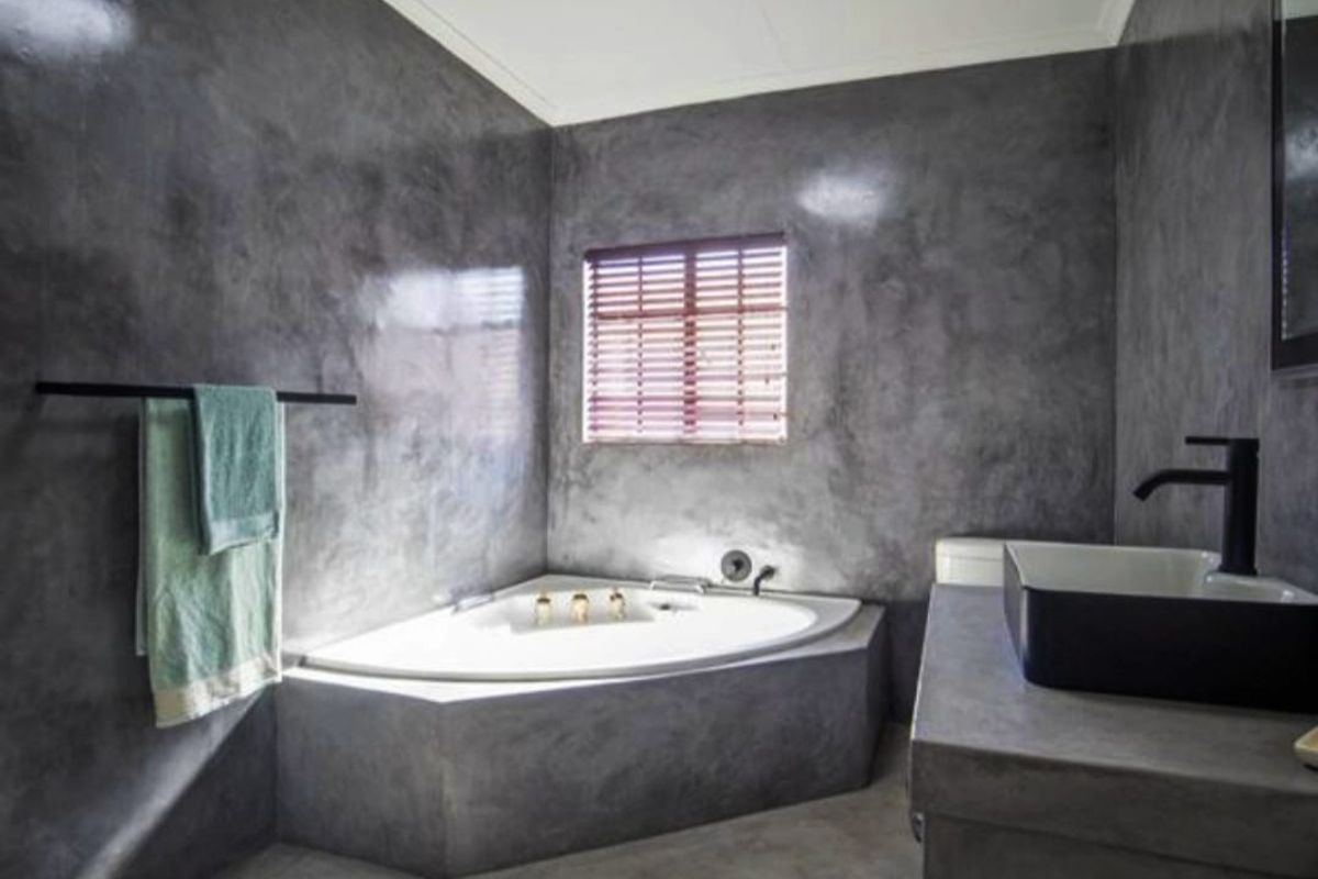 Modern bathroom featuring a corner bathtub, concrete-style wall finishes, a floating vanity with a vessel sink, and matte black fixtures.