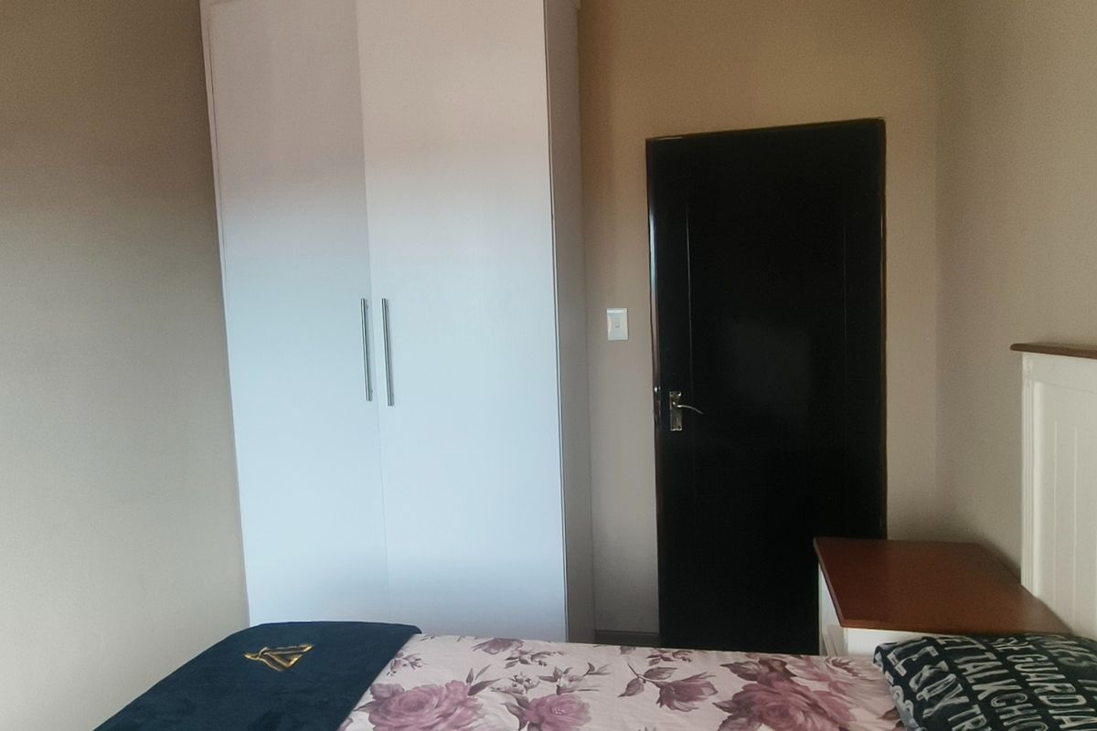 A bedroom featuring a built-in white wardrobe and a dark-finished interior door.