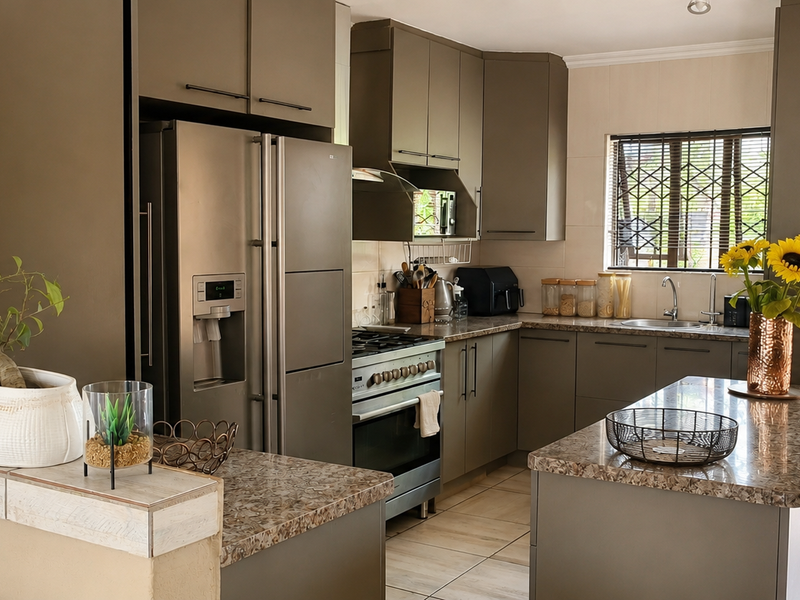 Modern kitchen featuring dark cabinetry, granite countertops, a stainless steel gas stove, and a functional island layout with direct access to the exterior.