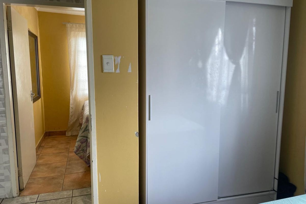 A view from a bedroom looking into an adjacent room, featuring tiled flooring and a built-in sliding door wardrobe.