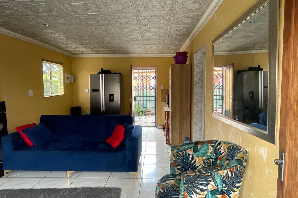 A living area featuring a decorative pressed metal ceiling, tiled flooring, and direct access to an exterior security gate.