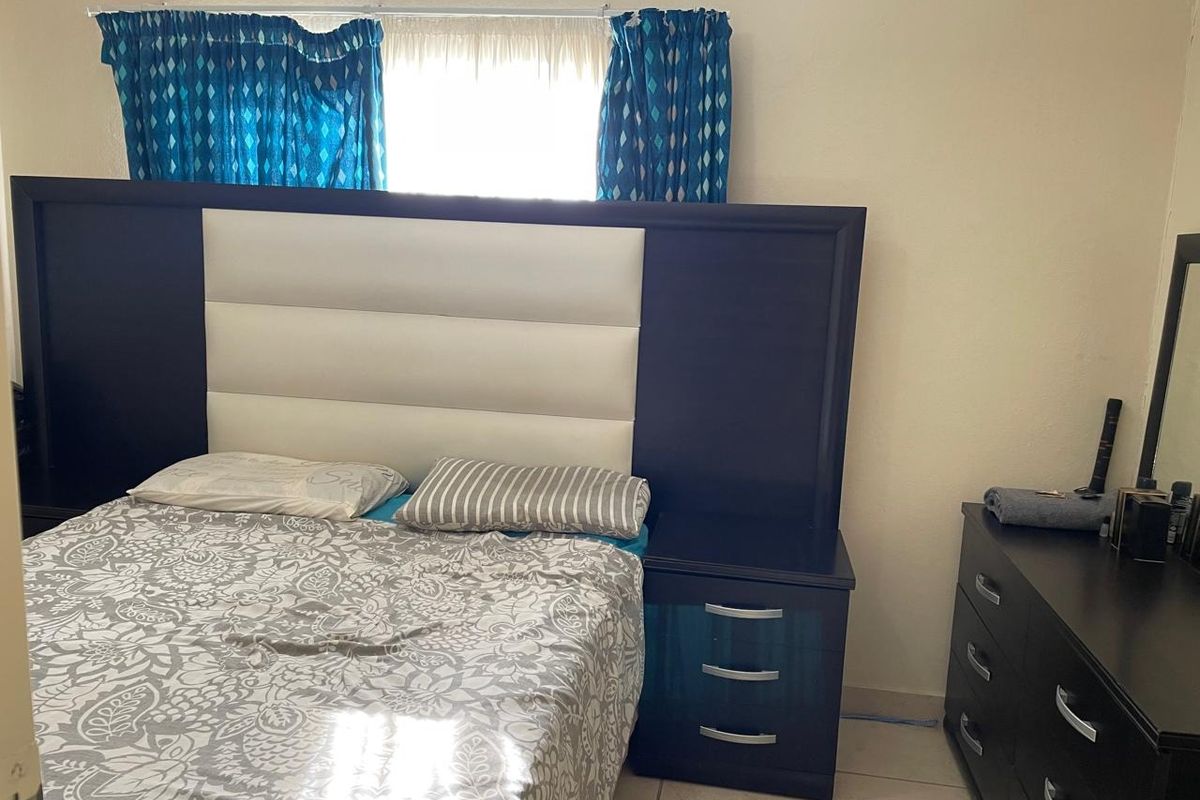 A bedroom featuring tiled flooring and a window with curtains.