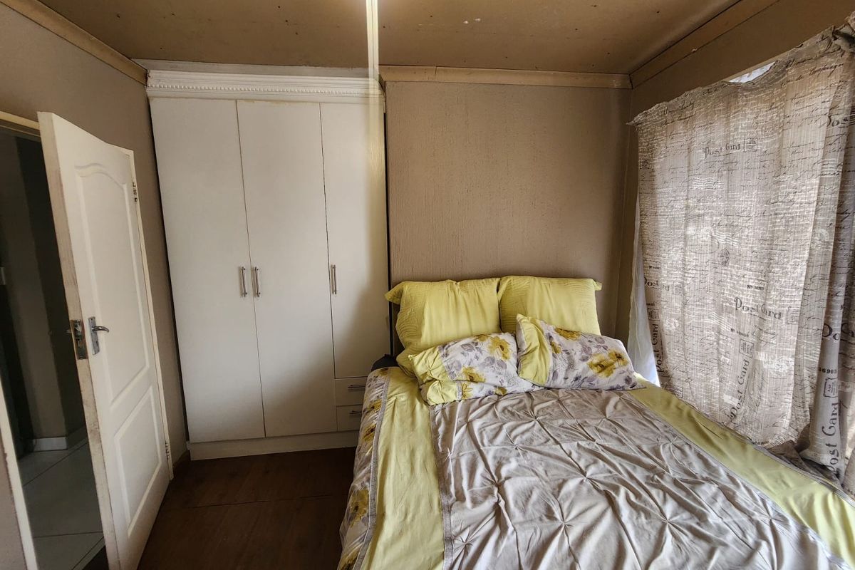 A bedroom featuring built-in white cabinetry and wood-look flooring, requiring ceiling finishing and cosmetic updates to improve the overall aesthetic.