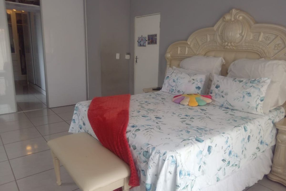Spacious bedroom featuring tiled flooring, built-in cupboards, and an adjoining walk-in closet area.
