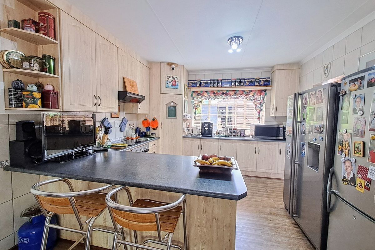 A functional kitchen featuring light wood-finish cabinetry, a breakfast bar with dark laminate countertops, and tiled flooring.