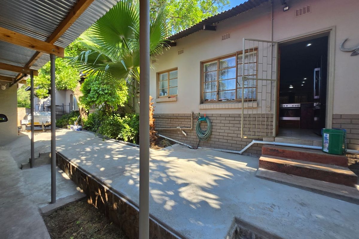 Rear exterior view featuring a concrete patio area, corrugated metal roof covering, and access to the interior living space.