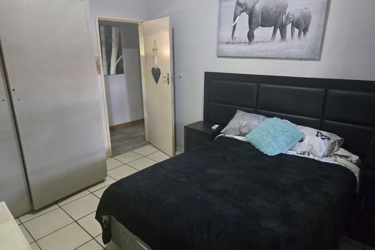A bedroom featuring tiled flooring and built-in wardrobe storage, with a doorway leading to an adjacent space.