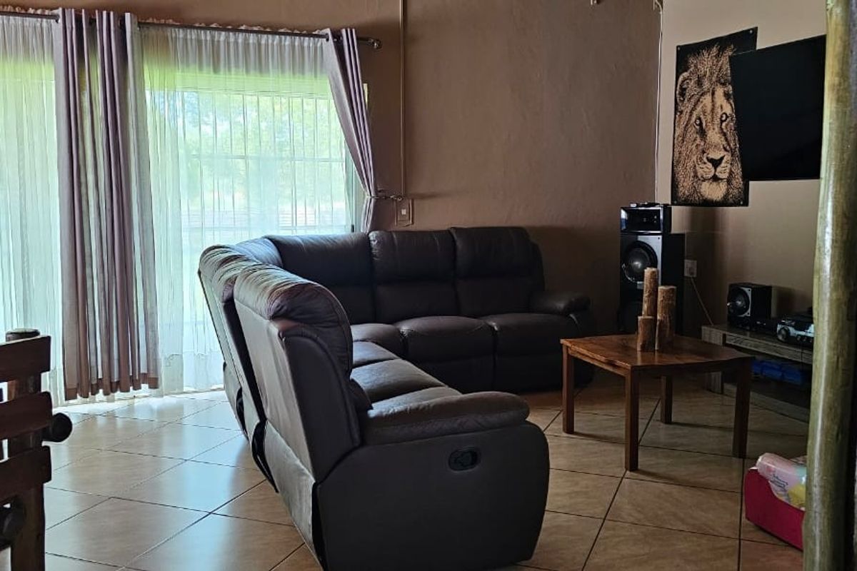 A comfortable living area featuring tiled flooring and large sliding glass doors that provide natural light and access to the exterior.