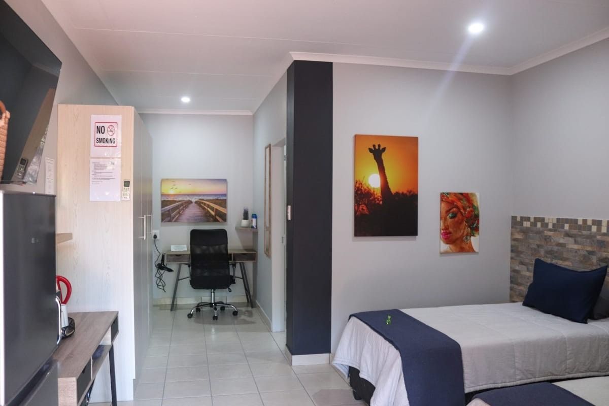 A well-maintained bedroom featuring tiled flooring, a stone-cladding feature wall behind the bed, and a dedicated built-in workspace area.