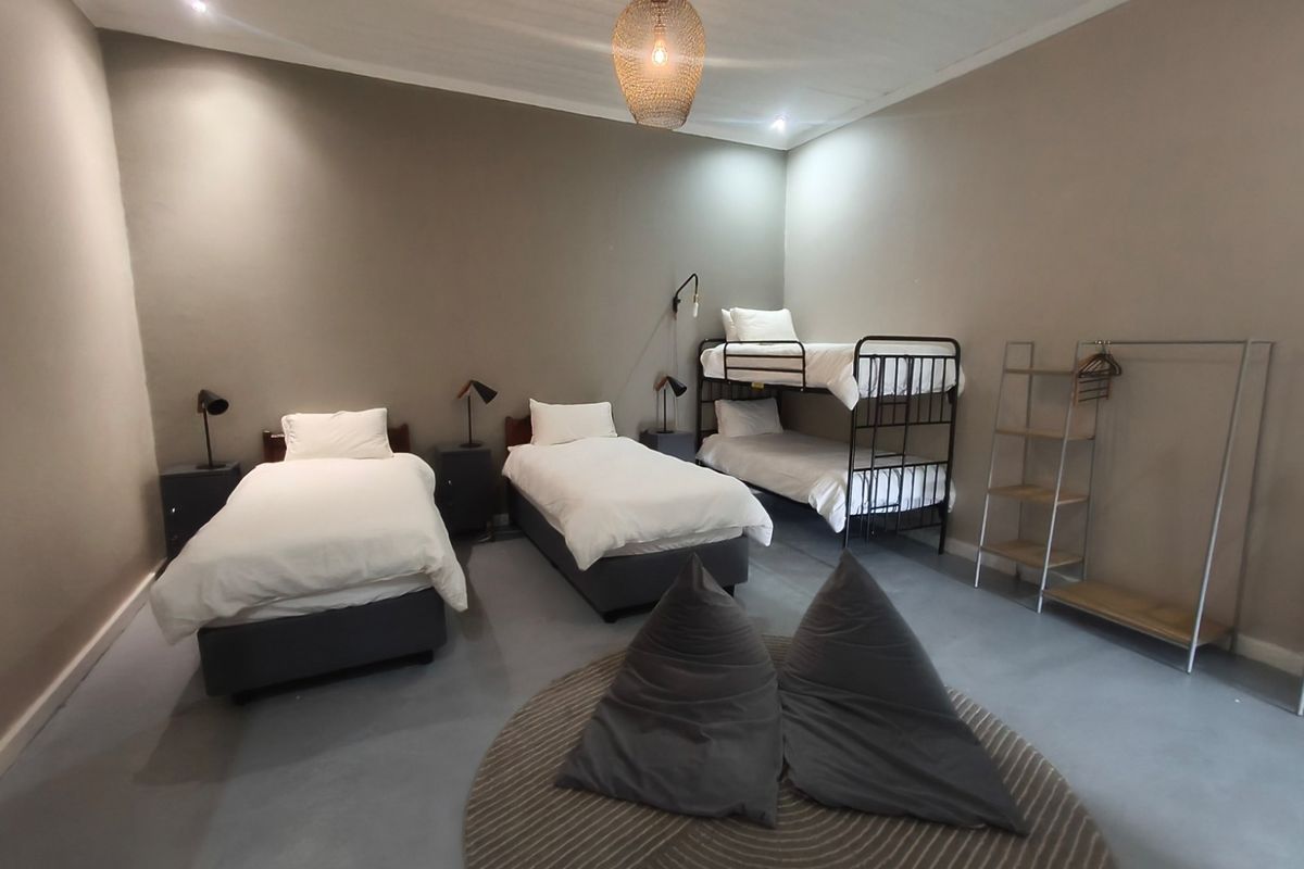 Spacious bedroom featuring smooth concrete flooring, neutral wall tones, and recessed ceiling lighting, designed to accommodate multiple beds.