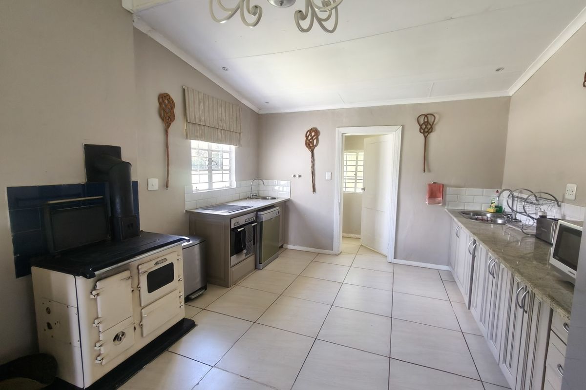 A functional farm-style kitchen featuring a classic wood-burning stove, granite countertops, tiled flooring, and ample cabinetry for storage.