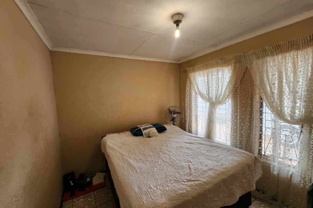 A bedroom featuring tiled flooring and security bars on the windows, requiring cosmetic updates to the walls and ceiling to improve its overall condition.