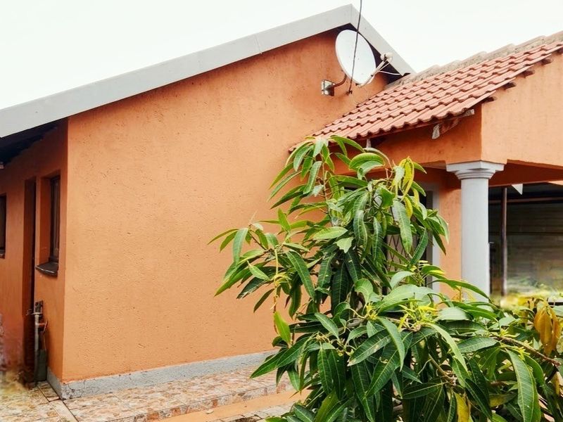 Rear exterior view of the house featuring a tiled patio, concrete columns, and a satellite dish mounted on the roof.