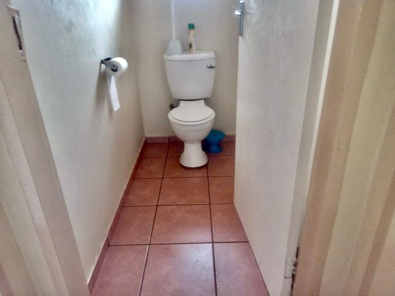 A compact guest toilet featuring ceramic floor tiles and a standard white porcelain toilet suite.