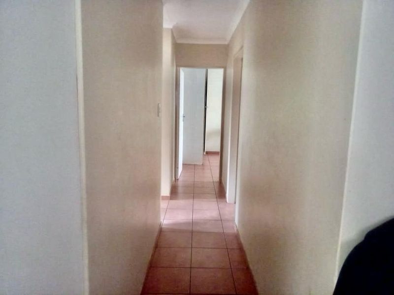 A simple interior hallway featuring tiled flooring and neutral wall finishes, providing access to adjacent rooms within the home.
