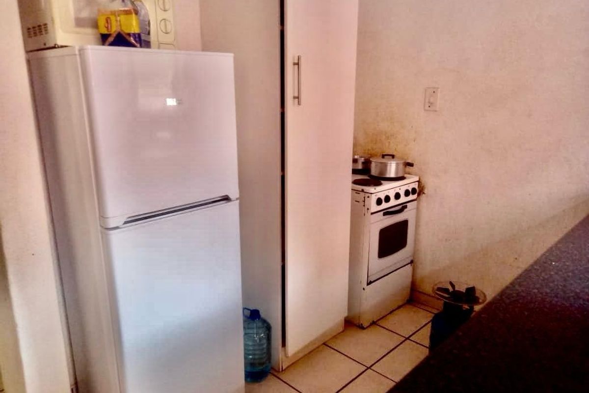 A compact kitchen area featuring tiled flooring, a freestanding stove, and built-in cabinetry.
