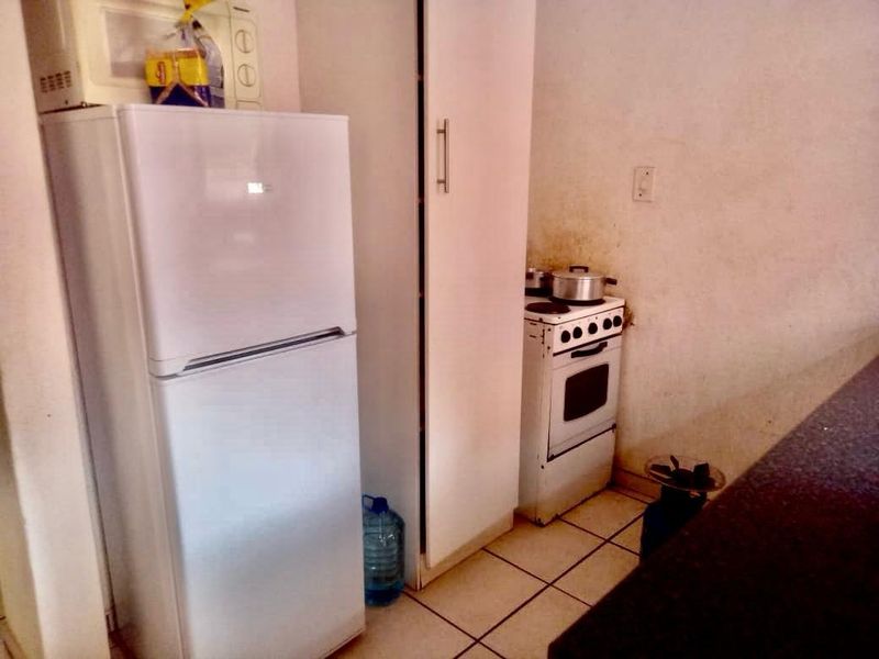 A compact kitchen area featuring tiled flooring, a freestanding stove, and built-in cabinetry.