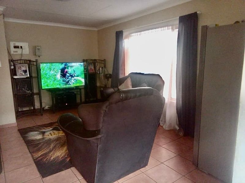 A living room featuring tiled flooring and a large window, providing a functional and comfortable space for relaxation.
