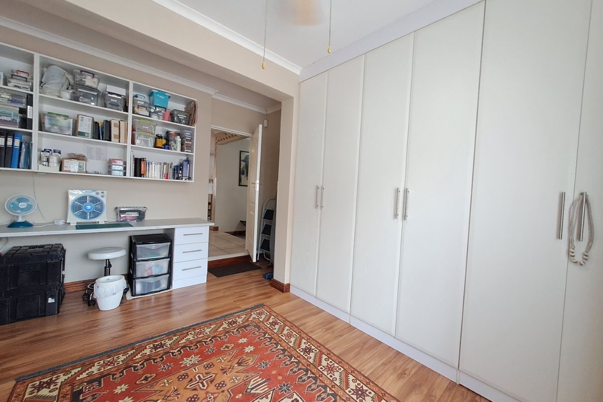 Bedroom featuring extensive built-in floor-to-ceiling wardrobes and a dedicated built-in desk area with overhead shelving.