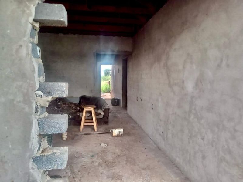 An unfinished interior space featuring exposed concrete block walls and an open ceiling structure, presenting a blank canvas for renovation.