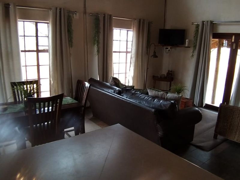 Open-plan living and dining area featuring tiled floors, large windows, and direct access to the outdoor patio through French doors.