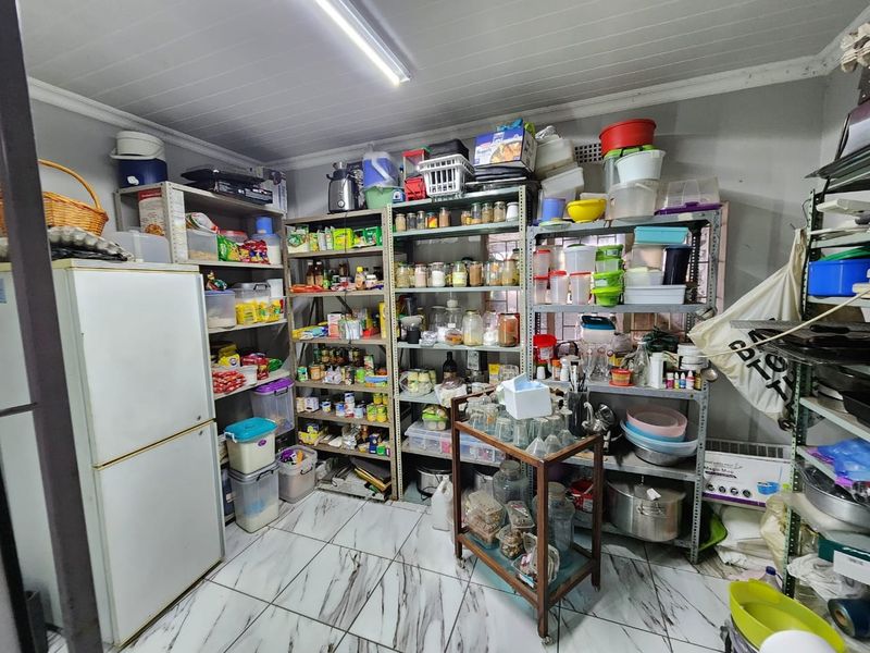 A functional scullery or pantry area featuring tiled flooring and ample storage shelving, providing practical utility space for household organization.
