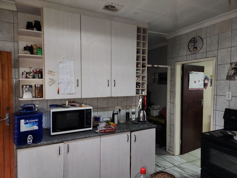 A functional kitchen featuring laminate cabinetry, tiled backsplash, and built-in oven, offering a practical layout with potential for modern cosmetic updates.