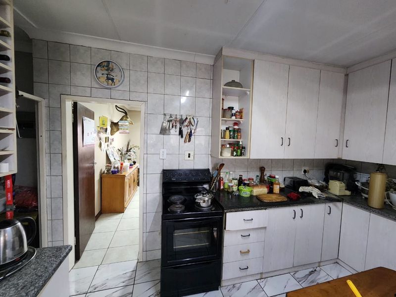 A functional kitchen featuring white cabinetry, tiled backsplash, and a freestanding stove, offering potential for modernization and aesthetic updates.