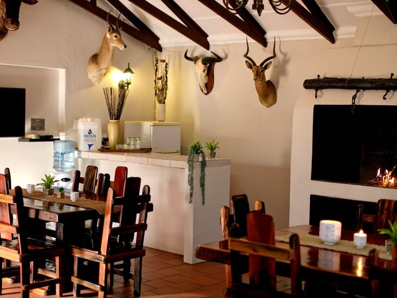Open-plan living and dining area featuring exposed timber ceiling beams, a built-in fireplace, and a service counter, creating a rustic farm-style atmosphere.