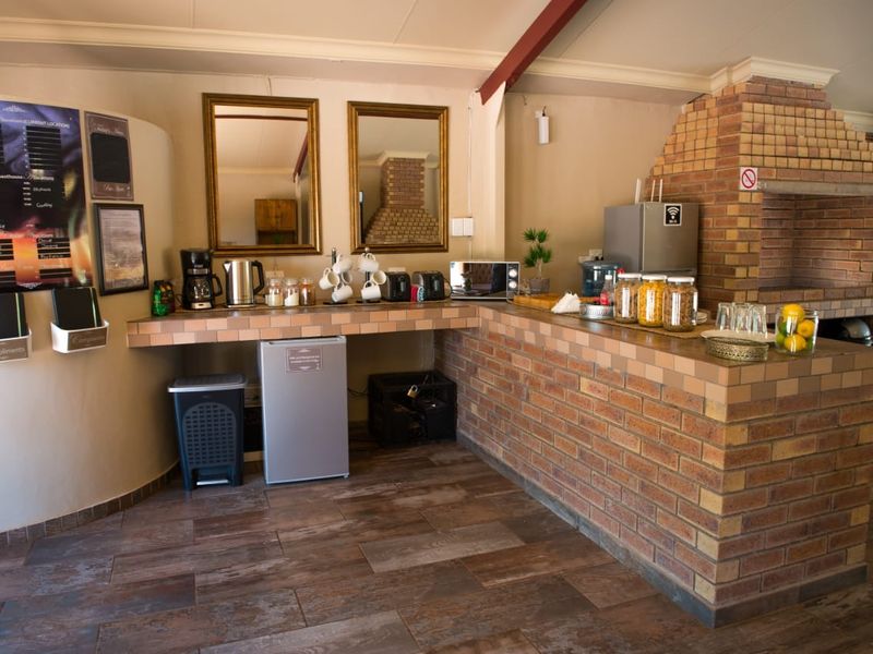 A rustic kitchen area featuring a prominent built-in brick fireplace, tiled countertops, and a brick breakfast bar with wood-look flooring.