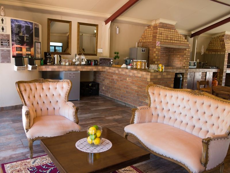 Open-plan living area featuring a rustic brick fireplace, tiled flooring, and exposed ceiling beams, creating a warm and inviting communal space.