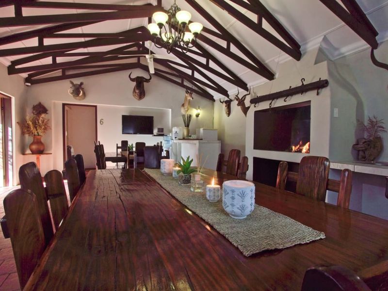 Spacious dining area featuring exposed timber roof trusses, a built-in fireplace, and tiled flooring, creating a rustic and inviting atmosphere.