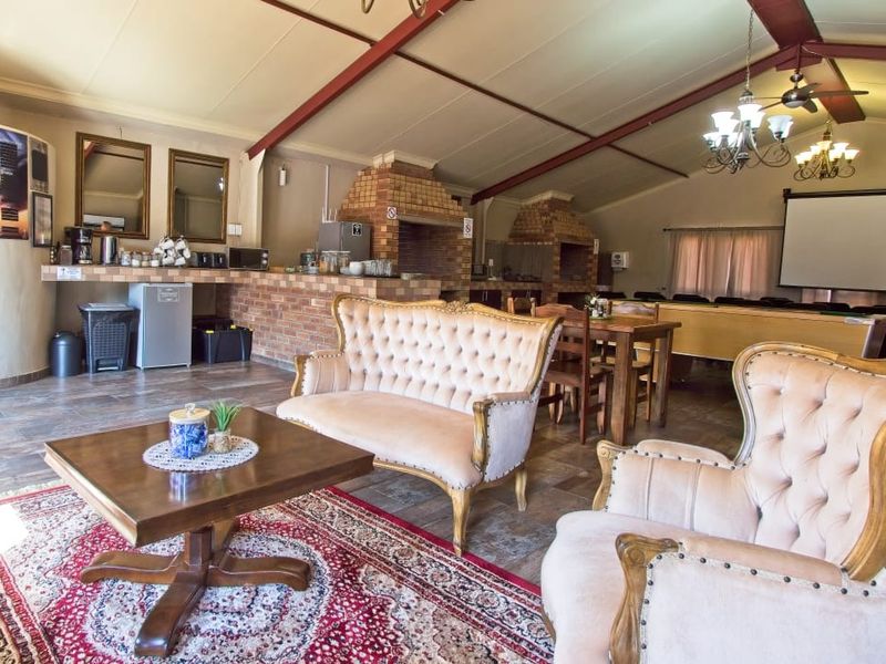 Spacious open-plan entertainment area featuring a large brick built-in braai, tiled flooring, and exposed roof trusses, ideal for hosting gatherings.