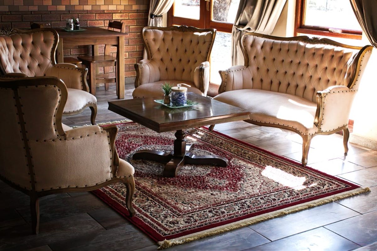 A cozy living area featuring exposed brick walls, tiled flooring, and timber-framed glass doors that provide natural light.